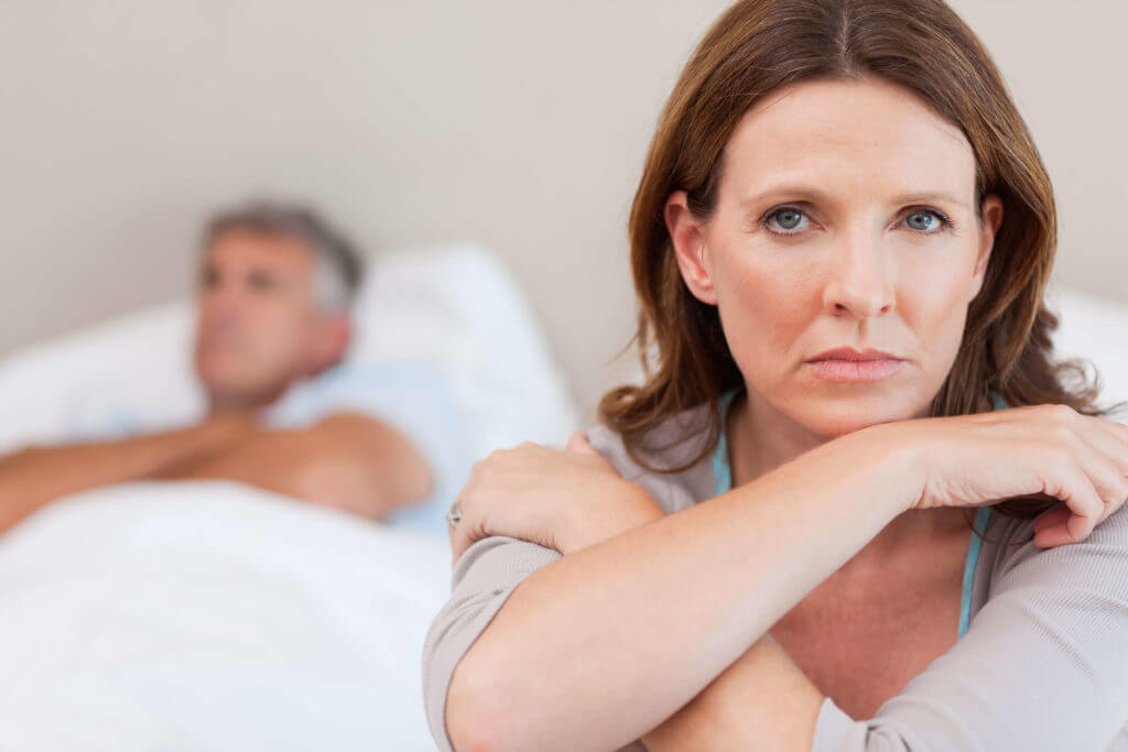 Concerned woman sitting beside her husband in a hospital bed